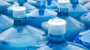 Close-up of multiple large blue water jugs with sealed caps, stored for emergency or bulk water supply.