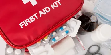 Flat lay of emergency medical supplies including bandages, pills, and first aid kit.