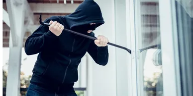 a person wearing black clothing breaking into a house